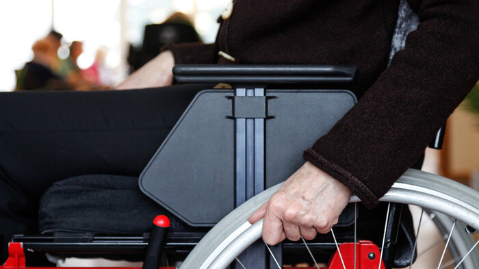 Bildet viser et utsnitt av en person som sitter i rullestol Bildet viser et utsnitt av en person som sitter i rullestol