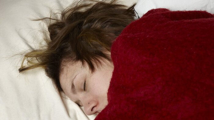 Bildet viser en syk kvinne som ligger i sengen
