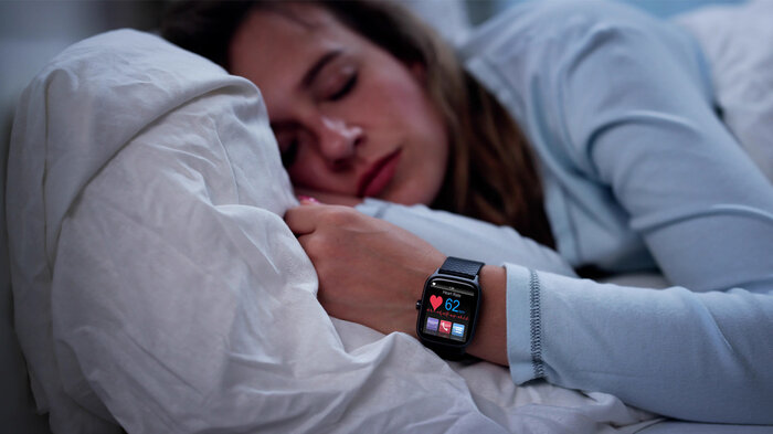 Kvinne som sover med smartklokke. Bildet viser en kvinne som sover med smartklokke.