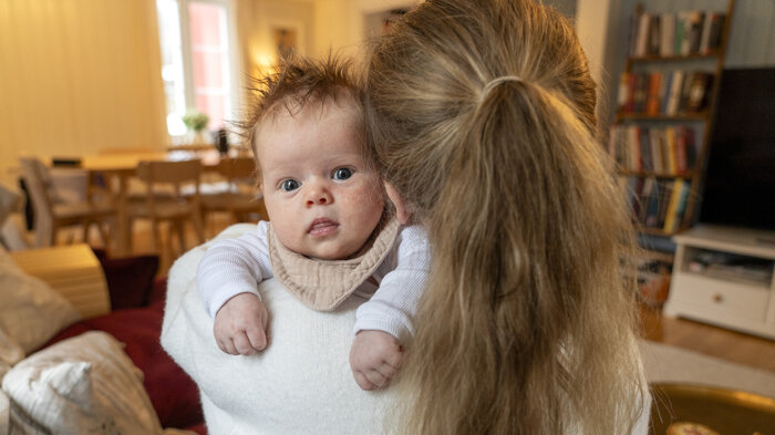 Bildet viser et spedbarn på mors arm.