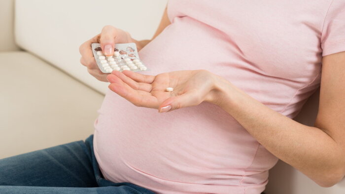 Bildet viser en gravid kvinne som tar tabletter