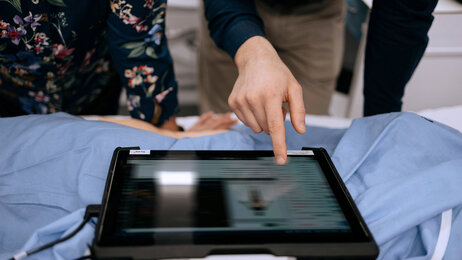 Bildet viser to mennesker som ser og peker på en iPad