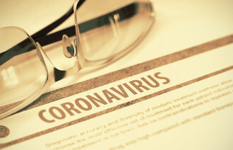 Bildet viser et par briller som ligger over en papirartikkel med overskrift Coronavirus.