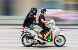 Bildet viser to på scooter som bruker munnbind.