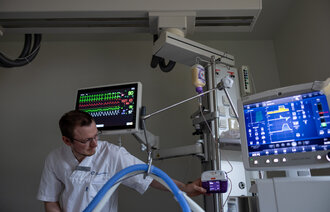 The picture shows a nurse preparing equipment for enteral nutrition in the intensive care unit.