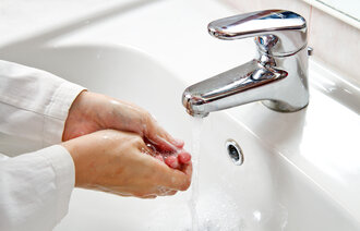 Bildet viser en pasient som vasker hendene i vasken