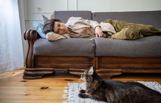 Bildet viser en kvinne som ligger på sofaen og ser pjusk ut.