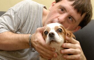 Mann med Downs syndrom koser med en hund.