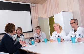 Møte mellom tverrfaglig helsepersonell. Bildet viser tverrfaglig helsepersonell som har møte rundt et bord.