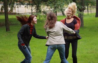 kvinner Tre kvinner danser i ring ute i en park