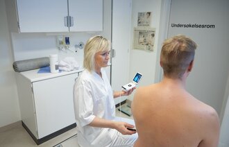Sykepleier Guri H. Gundersen tar ultralyd på en mannlig pasient.