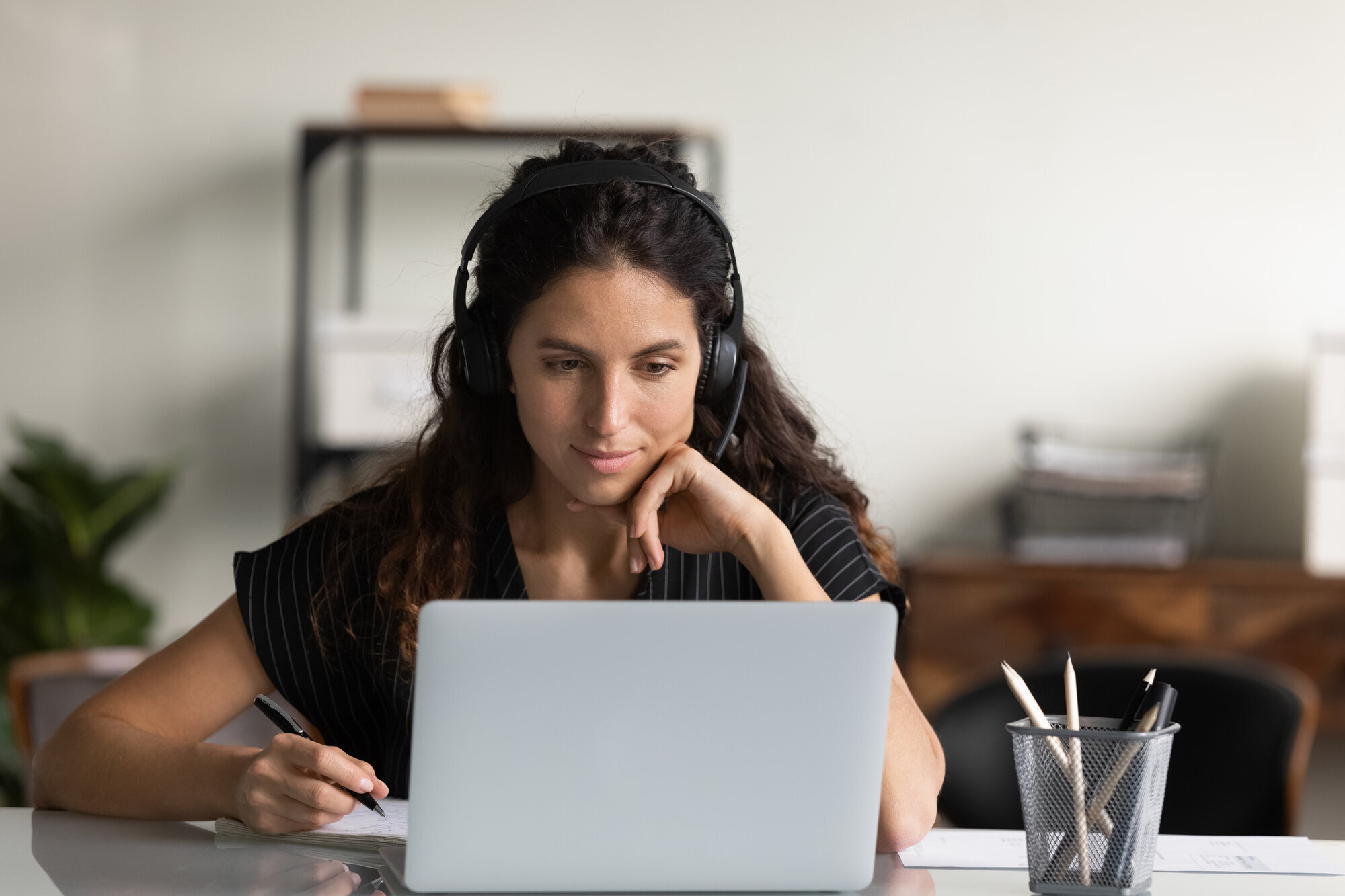 En ung kvinne med hodetelefoner ser på PC-en En ung kvinne med hodetelefoner ser på PC-en
