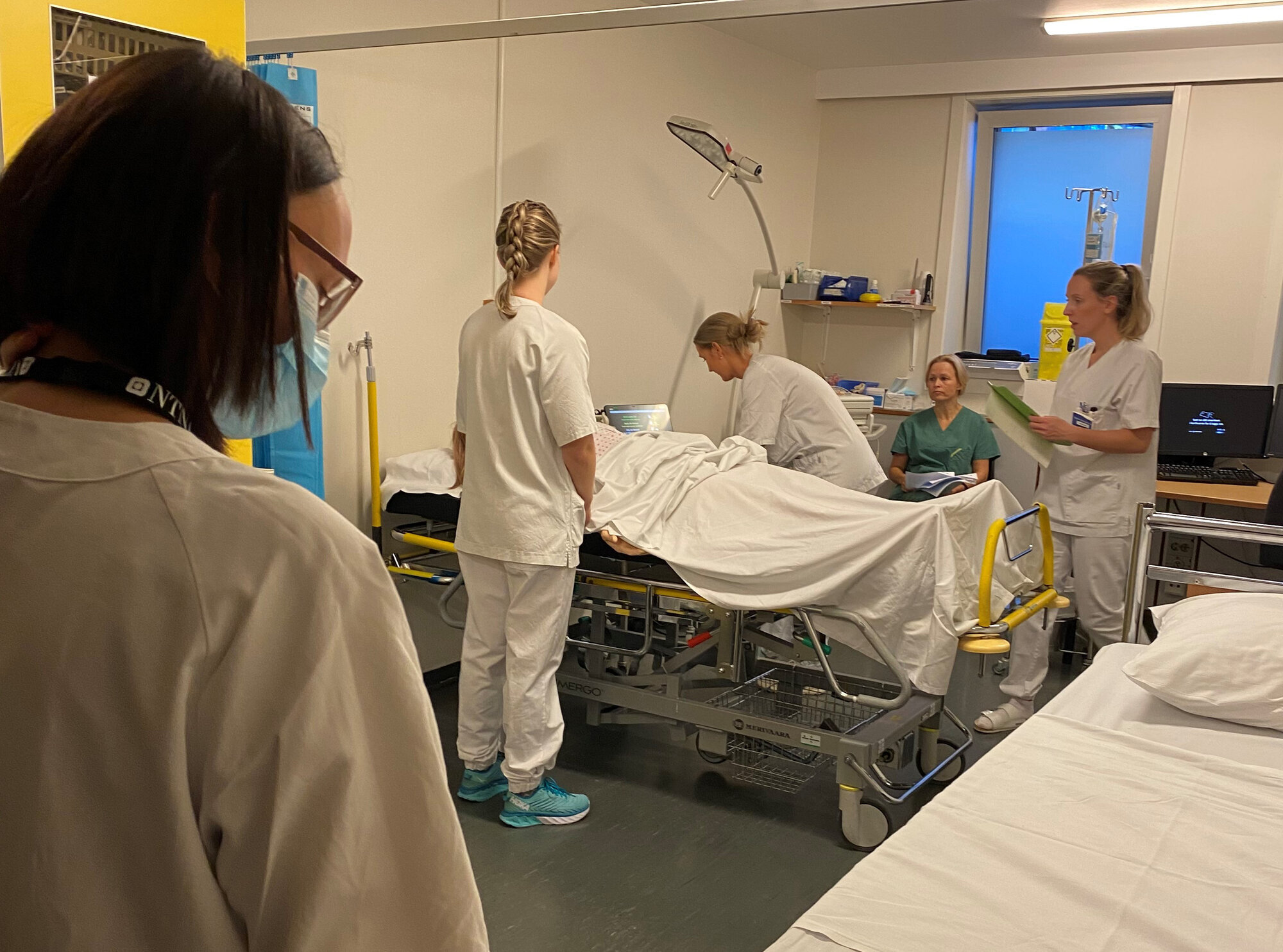 Veiledningssimulering En gruppe sykepleierstudenter øver sammen på en dukke.