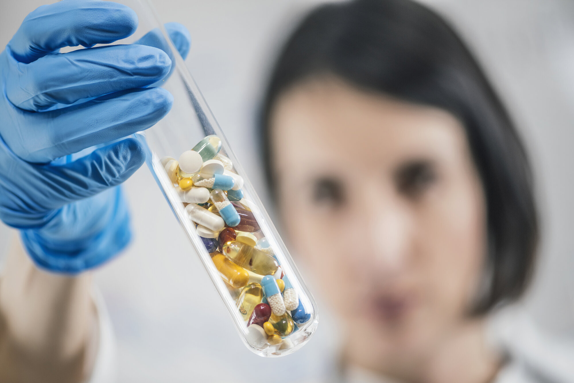Piller, antibiotika Bildet viser en kvinne som holder opp et glassrør med piller.