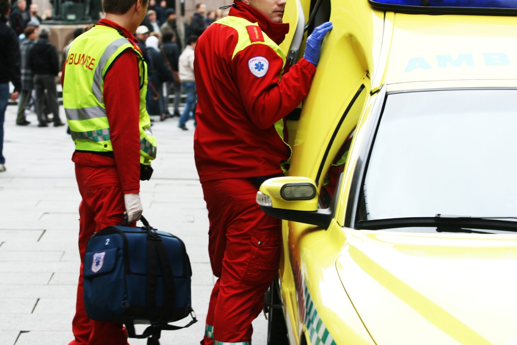 Bilde viser ambulansearbeidere som står utenfor ambulansen i et gatemiljø Bilde viser ambulansearbeidere som står utenfor ambulansen i et gatemiljø