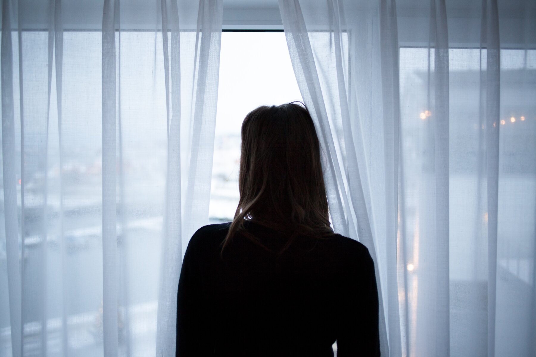 Viser en dame i motlys som står foran et vindu Viser en dame i motlys som står foran et vindu