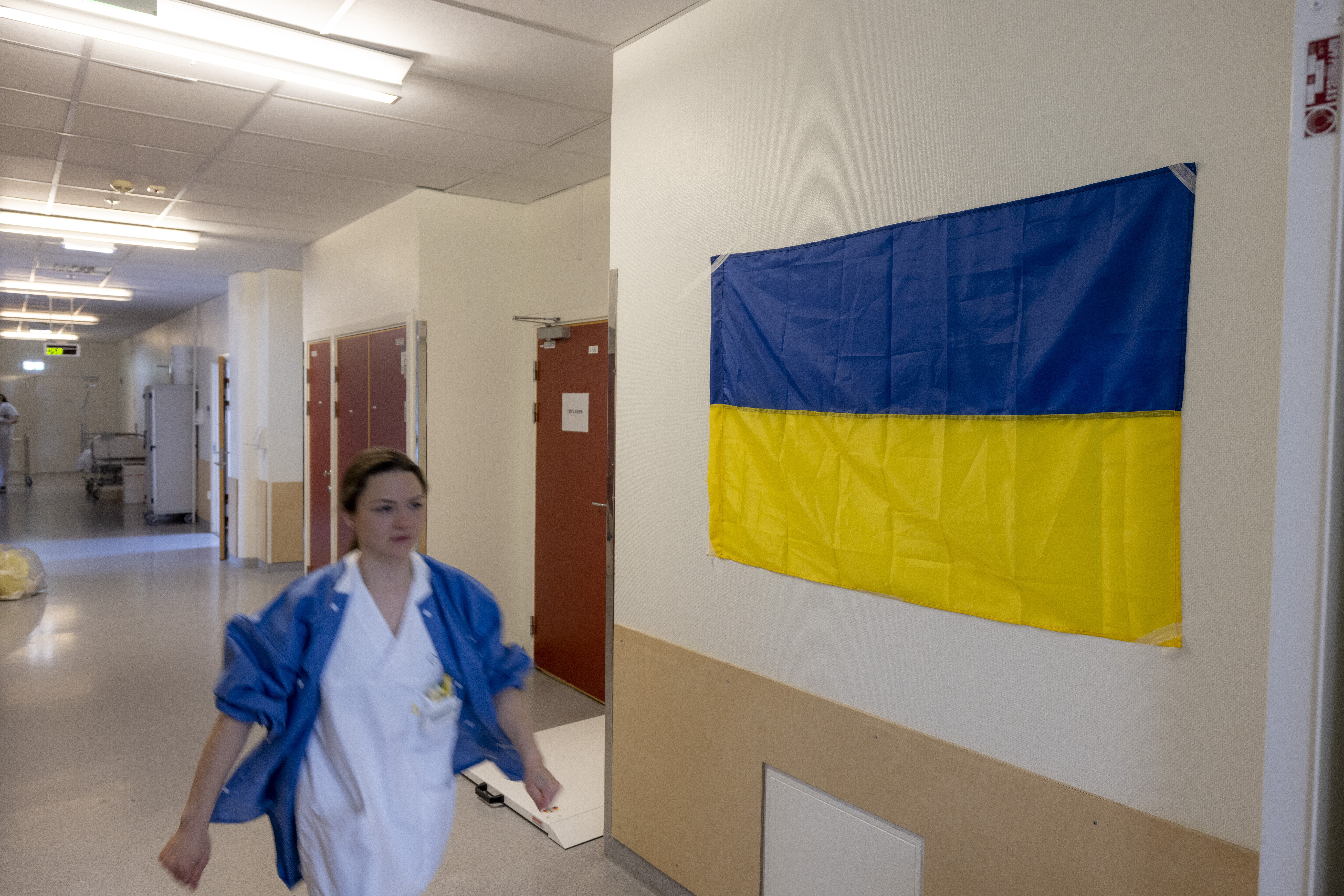 Sykepleier, Medevac Bildet viser en sykepleier i en gang med ukrainsk flagg på veggen.