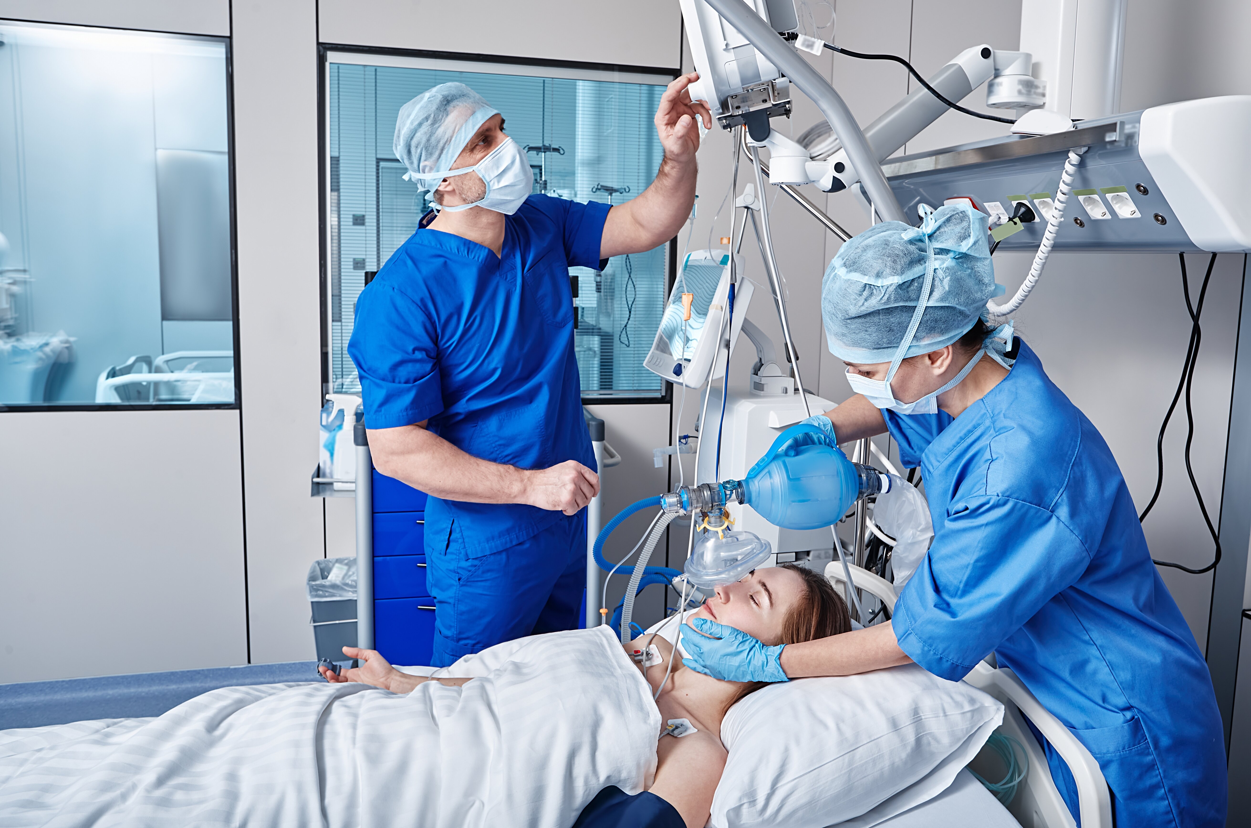 The photo shows two intensive care nurses standing by the bed of a patient being ventilated.