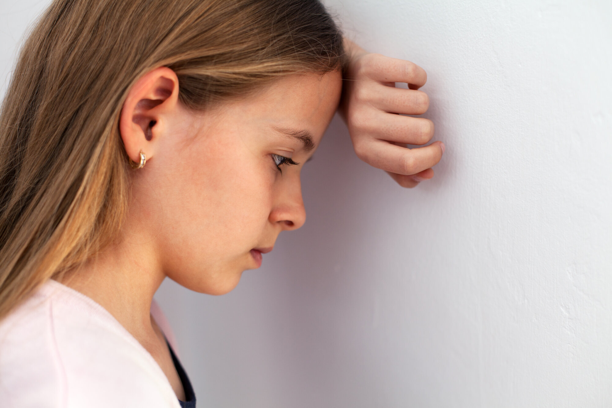 Bilde av tenåringsjente som lener hodet til en vegg Bilde av tenåringsjente som lener hodet til en vegg