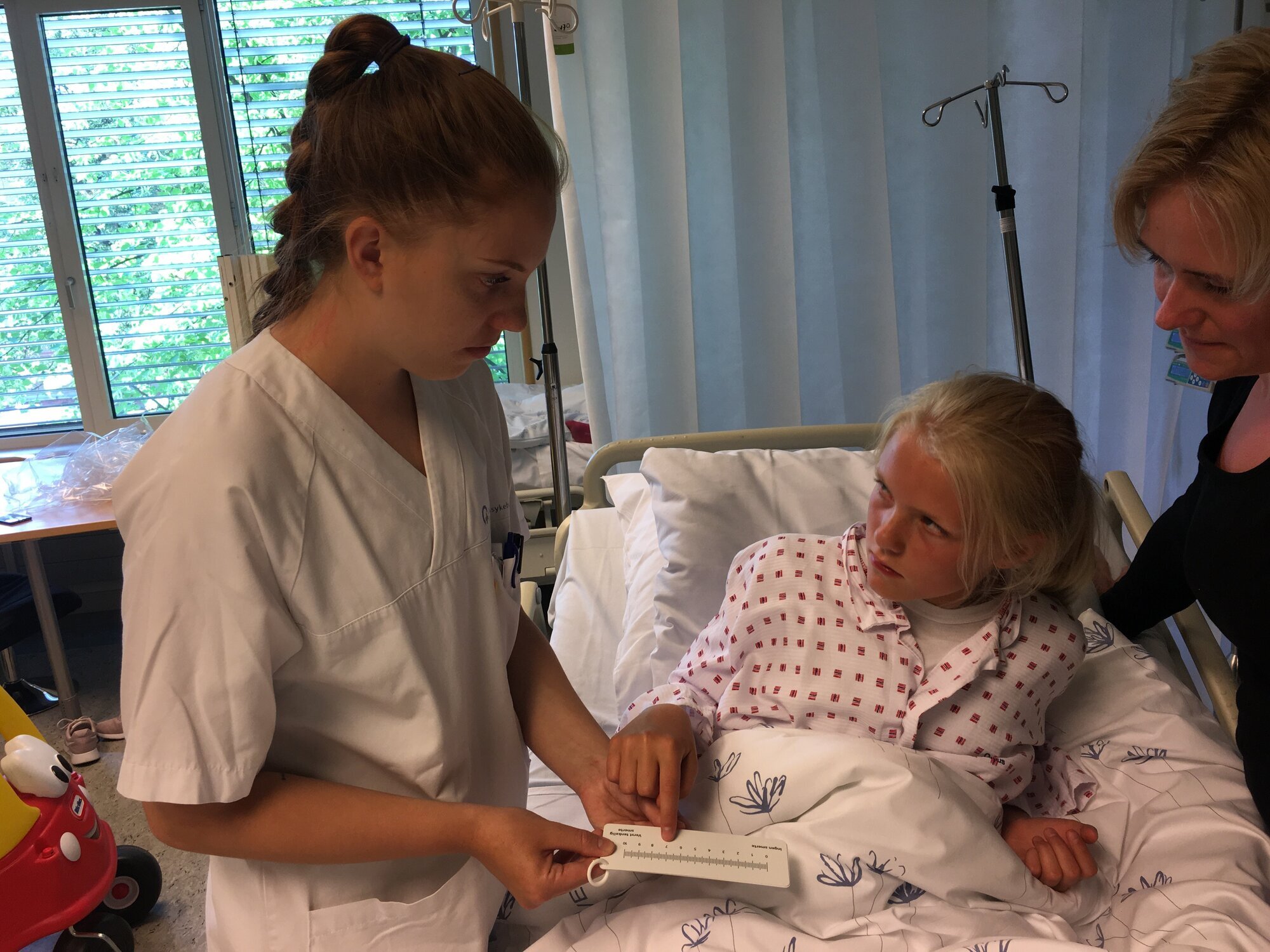 En ungdom på sykehuset forklarer sykepleier hvor vondt hun har det. En ungdom på sykehuset forklarer sykepleier hvor vondt hun har det.