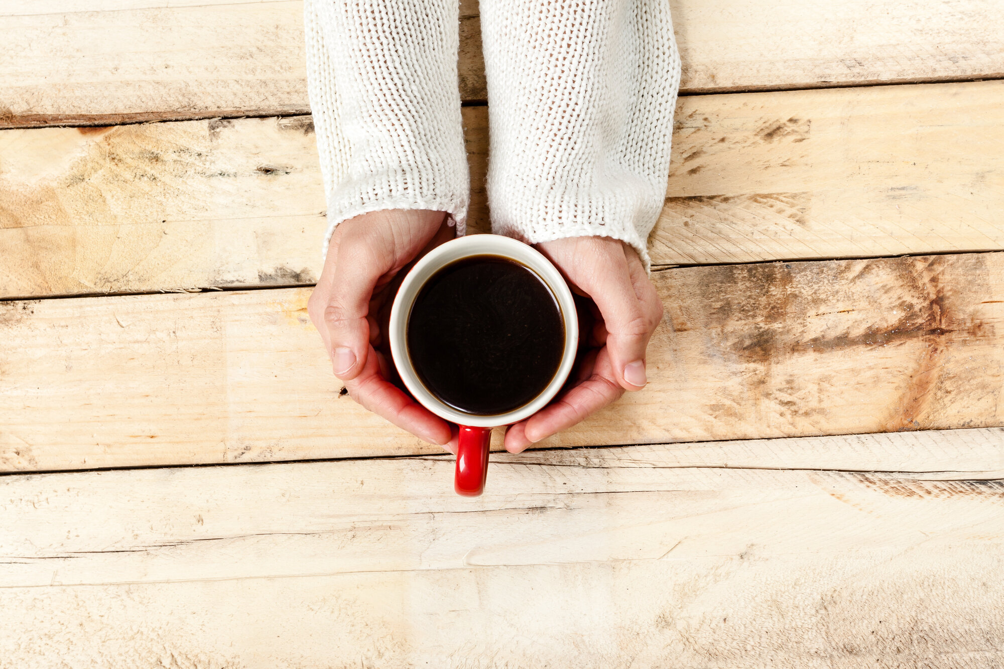 Kvinne med kaffe En kvinnes hender holder en kopp med kaffe på et rustikt trebord