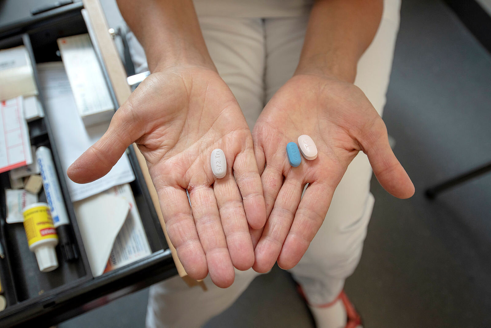 Bildet viser to hender som holder hiv-medisiner.

