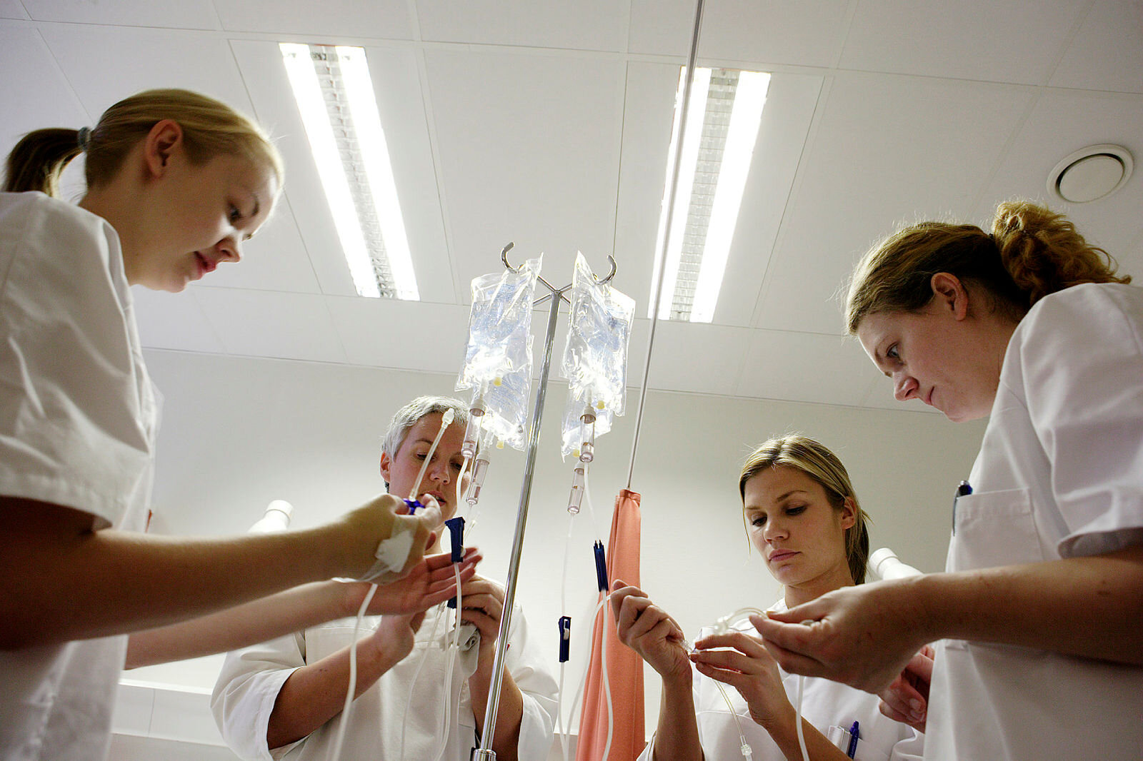 Bildet viser studenter i praksis som står med en væskepose over ei seng