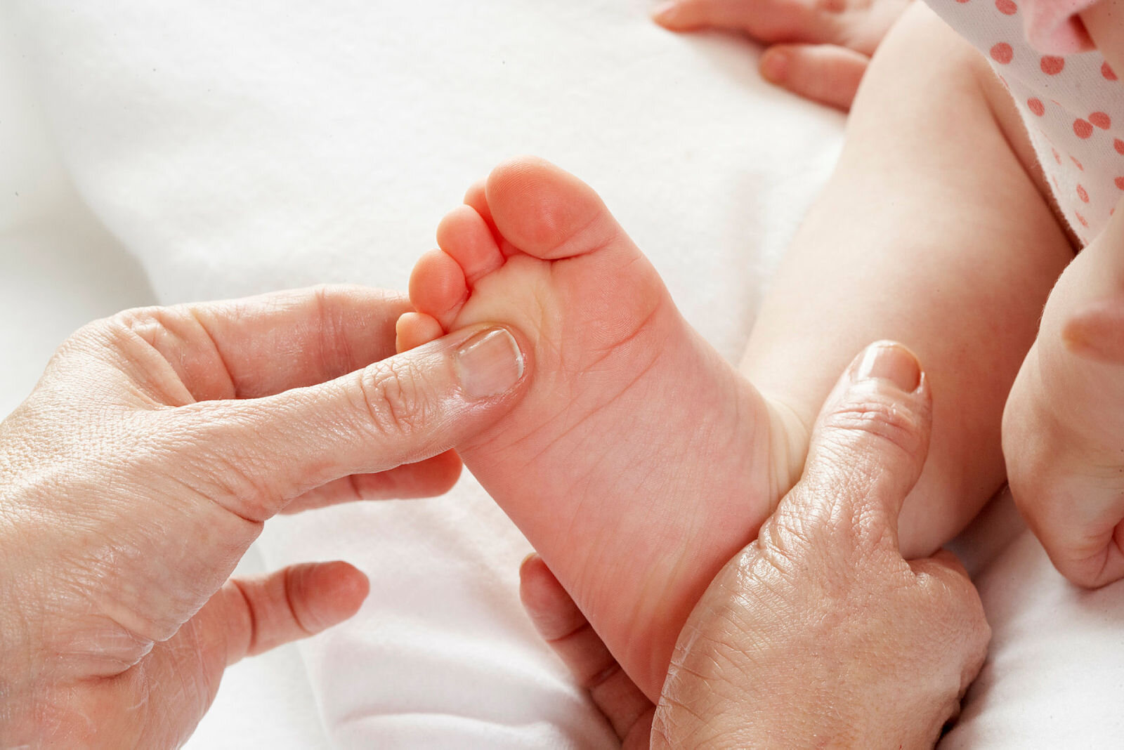 Baby som får fotmassasje Bildet viser en baby som blir massert på den høyre foten.