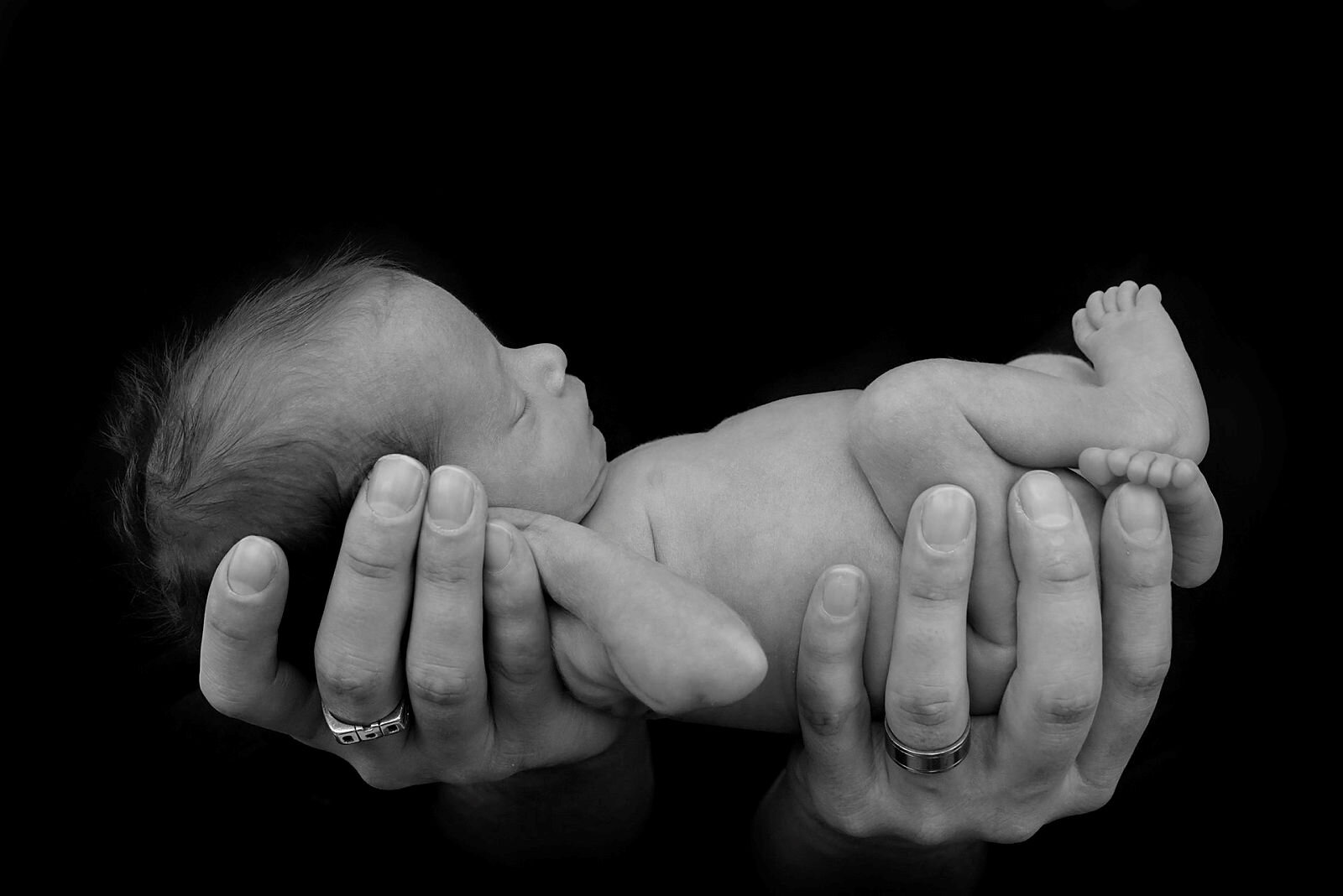 Et prematurt barn som holdes i sin fars hender.