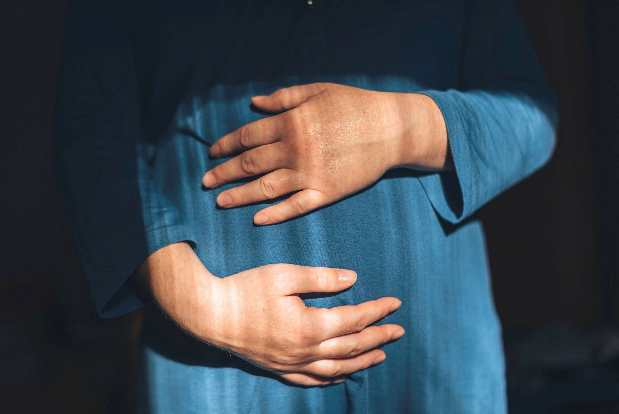 Gravid Gravid kvinne med hendene rundt magen.