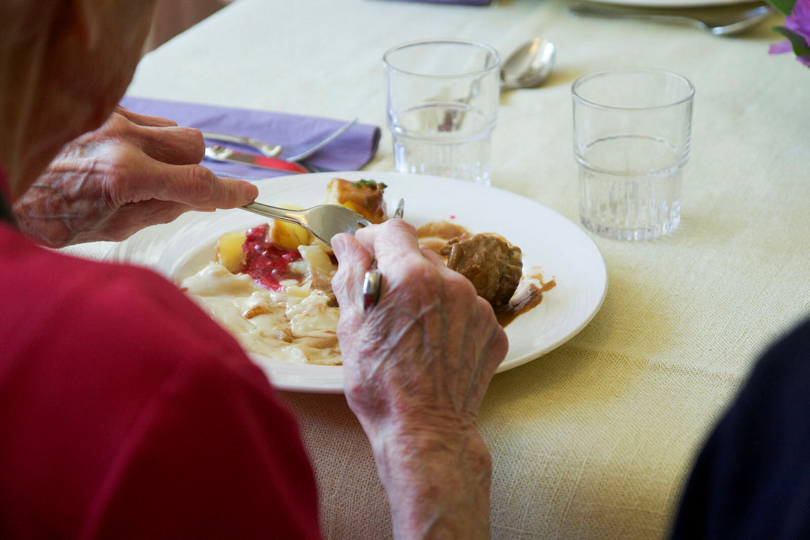 Bildet viser en eldre mann eller kvinne som spiser middag