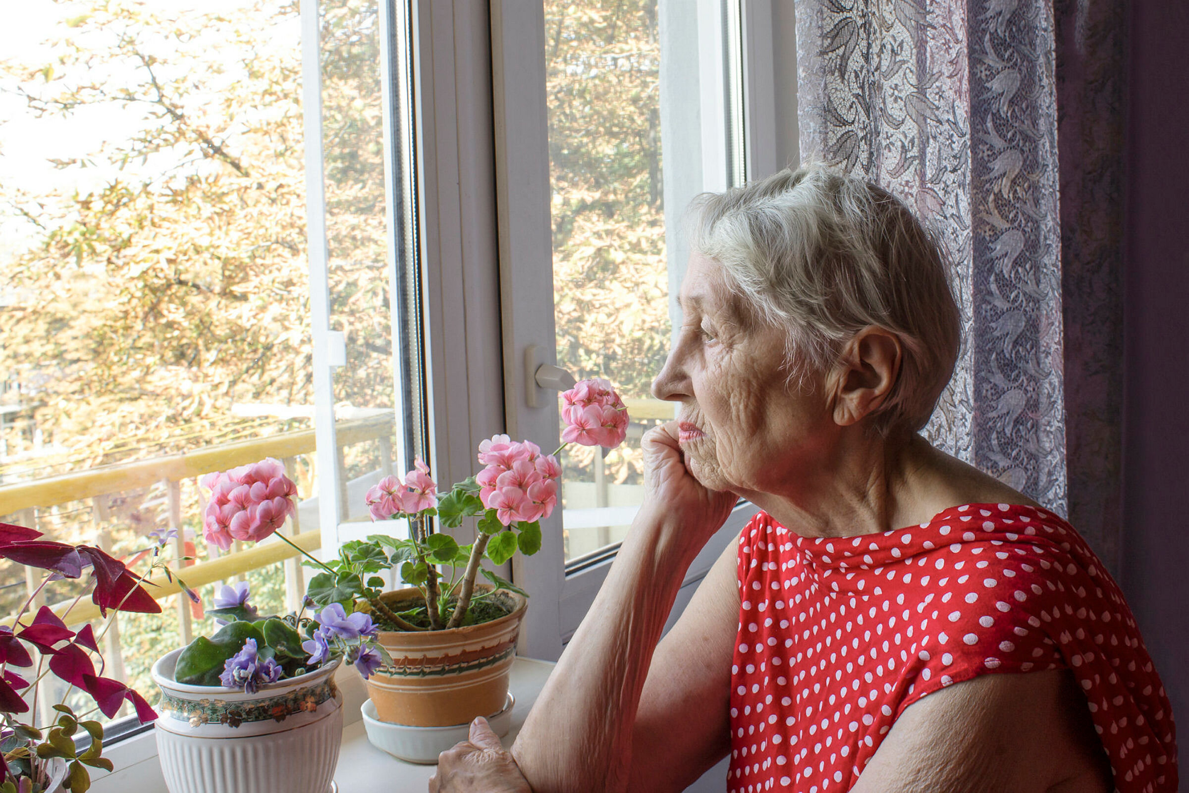 Eldre dame kikker ut av vindu