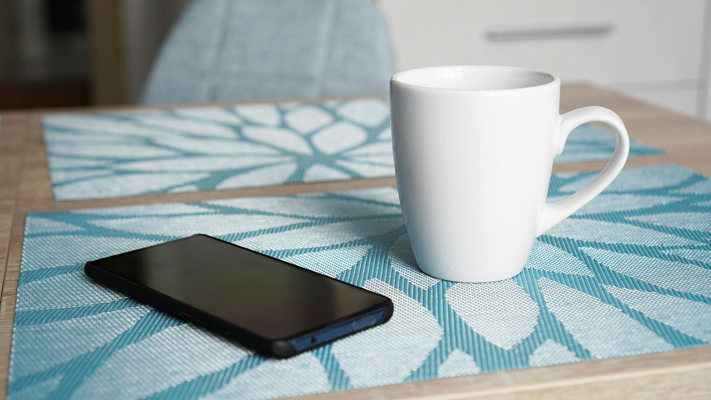Telefon og kaffekopp Mobiltelefon og kaffekopp på bord.