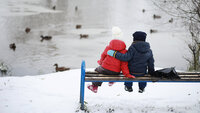 Barn på benk i parken Bildet viser to barn som sitter på en benk og ser på et vann med ender på