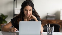 En ung kvinne med hodetelefoner ser på PC-en