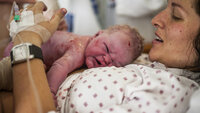Bildet viser en nyfødt baby som ligger på magen til moren