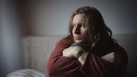 Bildet viser en tankefull mann som sitter i en seng