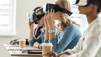 Bildet viser studenter med VR-briller på. De sitter ved sine pulter i et klasserom