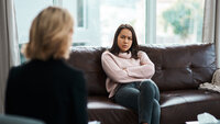 Sint pasient Bildet viser en person som sitter med ryggen vendt. Overfor henne sitter en ung jente som ser sint ut. Hun har armene i kors og et sint uttrykk i ansiktet.