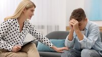 Bildet viser en helsesykepleier som trøster en skolegutt som er lei seg