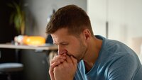 Bekymret mann Bildet viser en mann som ser bekymret ut. Han lener seg fremover og holder hendene knyttet foran ansiktet, lener seg mot hendene