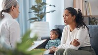 Bildet viser en mor og baby som sitter hos helsesykepleier