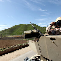 Bildet viser en tanks i Afghanistan. En norsk soldat står med kikkert opp av hullet i tanksen.
