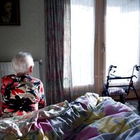 Bilde av eldre person på sengekanten på soverommet